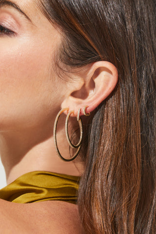 Image shows model in profile with four different varying size hoop earrings with pave cubic zirconia stones.