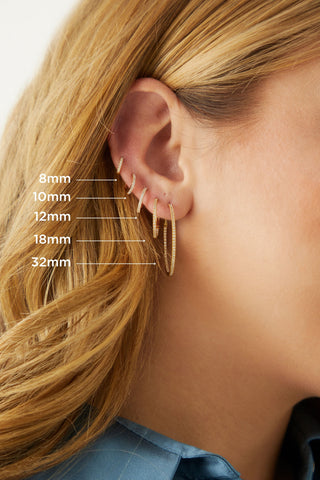 Image shows model in profile wearing five different 14 karat gold hoop earrings ranging in size from 8mm to 32mm