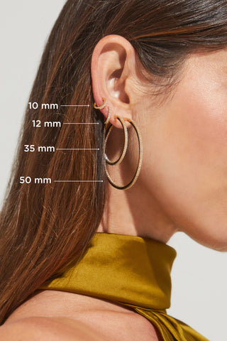 Image shows model's profile with four pave cubic zirconia hoop earrings ranging in size from 10mm to 50mm.
