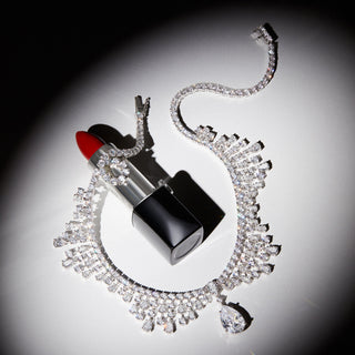 Image of Hollywood Statement necklace in a spotlight on top of a tube of red lipstick.