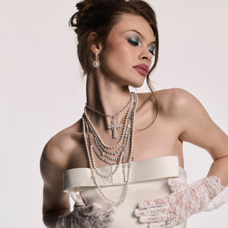 Image of model dressed in an edgy strapless white gown with lace gloves and Nadri's Material Pearl layered pearl necklace and earrings.