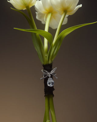 WHITE TULIPS WITH GREEN STEMS WRAPPED IN BLACK RIBBON, ADORNED WITH A CEREMONY SWAG BOW LAPEL PIN.