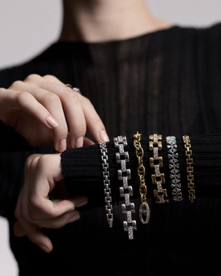  CLOSE UP OF A MODEL’S ARM EXTENDED IN FRONT OF HER, AS SHE WEARS A SHEER BLACK DRESS AND HAS BRACELETS FROM NADRI’S CELINE COLLECTION STACKED UP ALONG HER WRIST