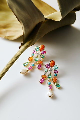 FRIEDA CHANDELIER EARRINGS NEXT TO A LARGE GREEN LEAF