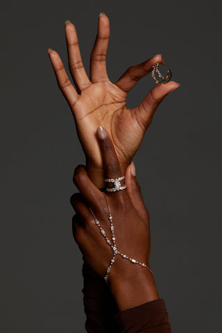 CLOSE UP OF HANDS WEARING THE EVERLEIGH HAND CHAIN BRACELET, OPEN RING, AND HOLDING THE MULTI C HOOP EARRINGS