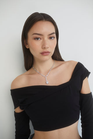 IMAGE OF MODEL WEARING THE RARE JEWELS MIXED-CUT CZ STATEMENT Y NECKLACE IN RHODIUM PLATING WITH A BLACK OFF THE SHOULDER TOP WITH CUT-OUT SLEEVES.