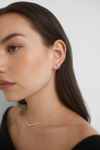 SIDE PROFILE IMAGE OF A MODEL WEARING THE RARE JEWELS FRONTAL NECKLACE WITH A BLACK OFF THE SHOULDER TOP AND THE RARE JEWELS CLIMBER CZ STUD EARRINGS. 