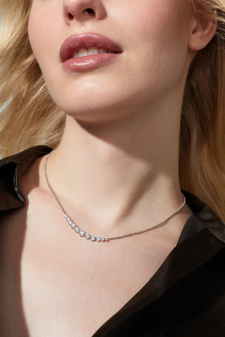 MODEL IS WEARING PERFECT TENNIS GRADUATED CZ FRONTAL NECKLACE IN RHODIUM PLATING WHILE LOOKING OFF TO THE SIDE. 