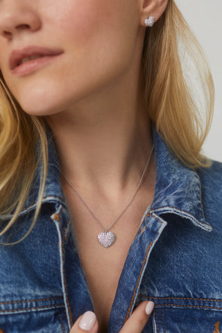 CLOSE UP IMAGE OF MODEL WEARING OUR GIFTED PAVE CZ HEART PENDANT IN RHODIUM PLATING WITH A DENIM JACKET.  SHE IS ALSO WEARING MATCHING EARRINGS.