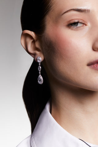 Close-up of a model wearing cz pear and oval drop earrings with a neutral background.