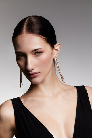 Image of a model in a black dress wearing long, dangling Hollywood Chandelier earrings with a neutral background.