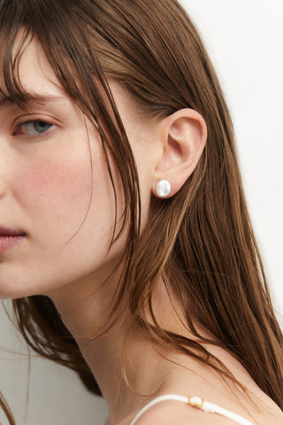 SIDE PROFILE OF A MODEL WEARING MADRID LARGE FRESHWATER PEARL STUD EARRINGS, WITH HER HAIR IN FRONT OF HER FACE