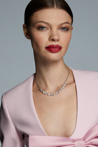 IMAGE OF MODEL WEARING LONDON MIXED CZ AND PEARL FRONTAL NECKLACE AND A PINK DRESS WITH A BOW DETAIL.  SHE IS LOOKING INTO THE CAMERA WITH A SOFT SMILE.