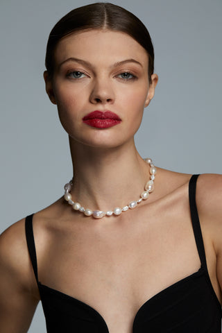 MODEL WEARING LONDON BAROQUE FRESHWATER PEARL COLLAR NECKLACE AND A BLACK DRESS AND FACING THE CAMERA. 