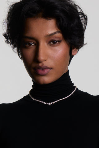A MODEL IN A BLACK TURTLENECK LOOKING AT THE CAMERA, WEARING THE ASTRID HEART TENNIS NECKLACE