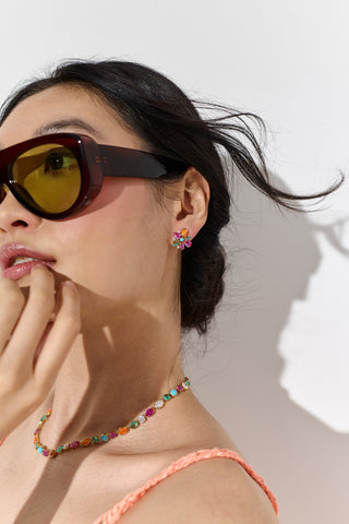 SIDE PROFILE OF A MODEL WITH HER HAND UP TO HER CHIN, WEARING THE FRIEDA FLORAL STUDS EARRINGS AND COLLAR NECKLACE