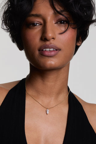 A MODEL LOOKING AT THE CAMERA WEARING THE LUCIA PEAR CZ PENDANT NECKLACE, STYLED WITH A BLACK HALTER NECK TOP