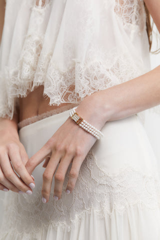 MODEL WEARING MADRID 4MM PEARL 3 ROW BRACELET WITH A WHITE LACE TOP AND SKIRT.