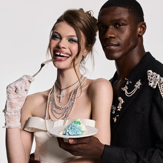 Bride and Groom holding a piece of cake wearing pearl and cz jewelry. 