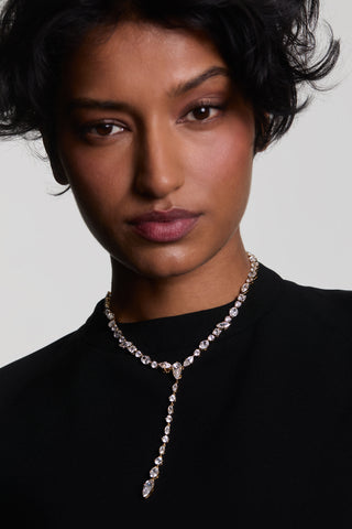 A MODEL LOOKING AT THE CAMERA WEARING THE RIVIERA CONVERTIBLE Y NECKLACE WITH THE Y-DROP ATTACHMENT, LAYERED OVER A BLACK TOP