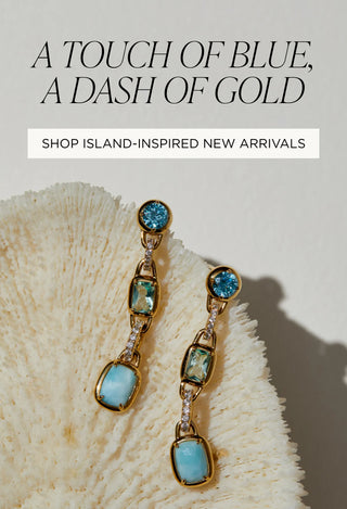 Image of blue toned linear earrings resting on a sea sponge, illustrating a beach-themed setting.  Text reads "A Touch of Blue, A Dash of Gold. Shop Island-Inspired New Arrivals".