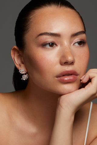 MODEL WEARING STELLAR HALO CZ JACKET EARRINGS WITH HER CHIN ON HER HAND AND HAIR PULLED BACK INTO A PONYTAIL. 