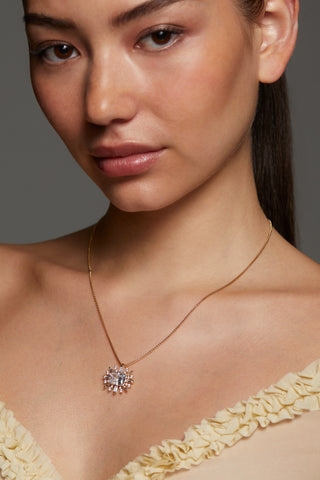 MODEL WEARING STELLAR CZ FULL HALO PENDANT NECKLACE. CLOSE UP IMAGE OF HER NECKLINE WITH HER HAIR PULLED BACK INTO A PONYTAIL. 