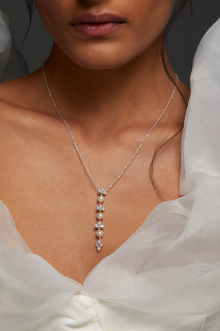 MODEL WEARING VENUS MULTI PEARL Y NECKLACE. IT IS A CLOSE UP IMAGE OF HER NECKLINE - SHE HAS ON A PUFFY WHITE GAUZE SLEEVES DRESS. 