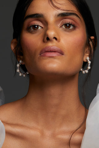 MODEL WEARING VENUS PEARL C HOOP EARRINGS. SHE IS LOOKING DIRECTLY TOWARD THE CAMERA WITH BOTH EARS VISIBLE. HER HAIR IS IN A LOW BUN. 