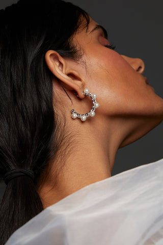 ALTERNATE IMAGE OF MODEL WEARING VENUS PEARL C HOOP EARRINGS. SHE IS LOOKING AWAY FROM THE CAMERA WITH HER EYES CLOSED. HER HAIR IS IN A LOW PONYTAIL. 