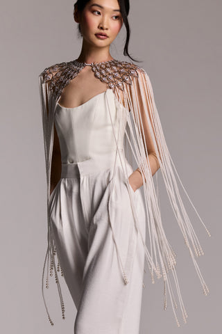 MODEL WEARING WHITE TROUSERS AND A WHITE TOP WITH THE PEARL AND CZ CAPE DRAPED OVER HER SHOULDERS, AS THE CASCADING PEARL FRINGE MOVES WITH HER STEP