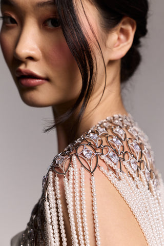 CLOSE-UP OF A MODEL LOOKING OVER HER SHOULDER WEARING THE PEARL AND CZ CAPE, HIGHLIGHTING THE PEAR-SHAPED RHODIUM CASTINGS AND CZ DETAILS