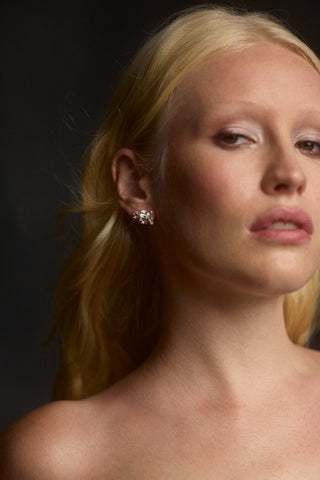 A MODEL LOOKING AT THE CAMERA, WITH HER BLONDE HAIR BLOWING BEHIND HER AS SHE WEARS THE CANNES STUD EARRINGS