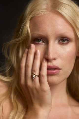 A MODEL LOOKING AT THE CAMERA WITH HER HAND LIFTED UP TO COVER HALF OF HER FACE, AS SHE WEARS THE CANNES SMALL STACK RING
