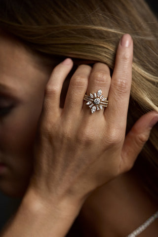 CLOSE UP OF A MODEL'S HAND BRUSHING HER BLONDE HAIR BEHIND HER EAR, AS SHE WEARS THE CANNES LARGE STACK RING