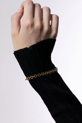 CLOSE UP OF A HAND AGAINST A WHITE BACKGROUND, WEARING A SHEER BLACK SLEEVE AND THE CELINE SMALL WATCH CHAIN BRACELET