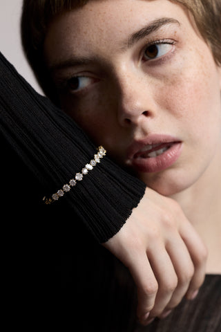 CLOSE UP OF A MODEL’S FACE AS SHE LIFTS UP HER HAND NEXT TO HER CHEEK, WEARING A SHEER BLACK DRESS AND THE CELINE MULTI CZ HINGE BRACELET