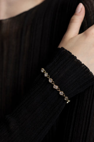 CLOSE UP OF A MODEL’S WRIST RESTING AGAINST HER SHOULDER, AS SHE WEARS A SHEER BLACK DRESS AND THE CELINE MULTI CZ LINE BRACELET