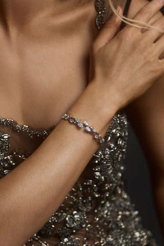 CLOSE UP OF A MODEL’S WRIST LIFTED ACROSS HER CHEST, WEARING A BLACK SHEER DRESS AND THE HERA BOTTOM HINGE BRACELET