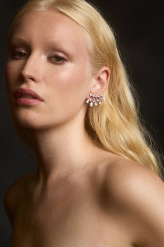 A MODEL WITH BLONDE HAIR LOOKING AT THE CAMERA AND WEARING THE HERA CLIMBER EARRINGS