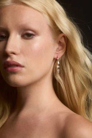 CLOSE UP OF A MODEL WITH BLONDE HAIR WEARING THE HERA ELONGATED C HOOP EARRINGS