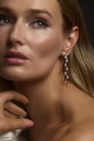 CLOSE UP OF A MODEL WITH BLONDE HAIR LOOKING OFF TO THE SIDE, WEARING THE HERA DOUBLE LINEAR EARRINGS