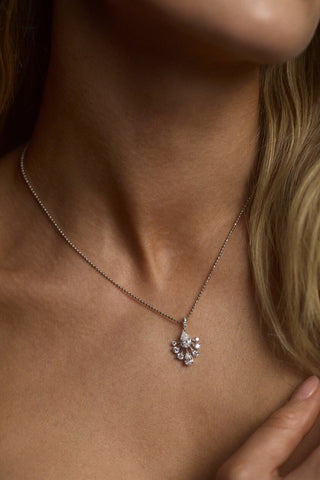 CLOSE UP OF A MODEL’S NECK WITH HER BLONDE HAIR IN FRAME WEARING THE HERA FAN PENDANT NECKLACE