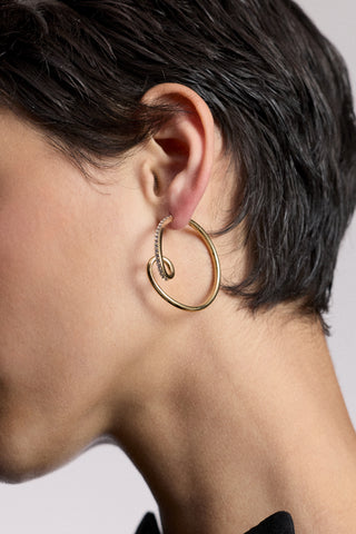 CLOSE UP OF A MODEL’S EAR WITH SHORT BLACK HAIR WEARING THE MUSE SWIRL HOOP EARRINGS