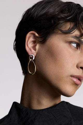 SIDE PROFILE OF A MODEL TURNED TO THE SIDE, AS SHE WEARS A BLACK TOP AND THE MUSE DOOR KNOCK EAR EARRINGS