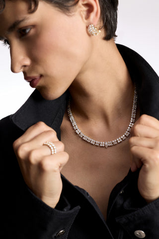 A MODEL WITH HER HEAD TURNED TO THE SIDE, WEARING THE TWINNIE STATEMENT COLLAR NECKLACE AND AN OPEN BLACK SHIRT, AS SHE PULLS ON THE SHIRT COLLAR 