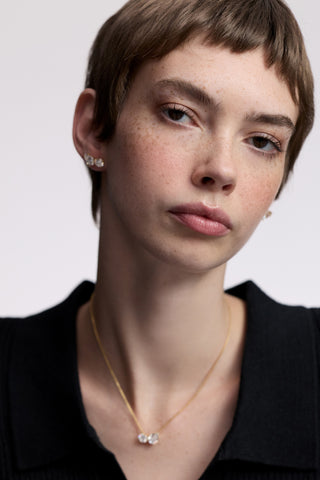 A MODEL WITH SHORT RED HAIR LOOKING AT THE CAMERA, AS SHE WEARS A BLACK TOP AND THE TWINNIE TOI MOI STUD EARRINGS