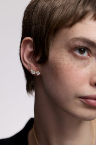 A MODEL WITH SHORT RED HAIR, WITH HALF OF HER FACE IN FRAME, AS SHE WEARS THE TWINNIE TOI MOI STUD EARRINGS