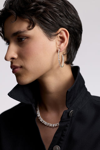 SIDE PROFILE OF A MODEL WITH SHORT BLACK HAIR AND A POPPED COLLAR, AS SHE WEARS THE TWINNIE C HOOP EARRINGS AND TWINNIE STATEMENT COLLAR NECKLACE
