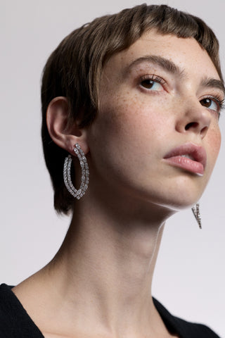 CLOSE UP OF A MODEL LOOKING OFF TO THE SIDE, WEARING A BLACK TOP AND THE TWINNIE FRONTBACK PATTERN HOOP EARRINGS